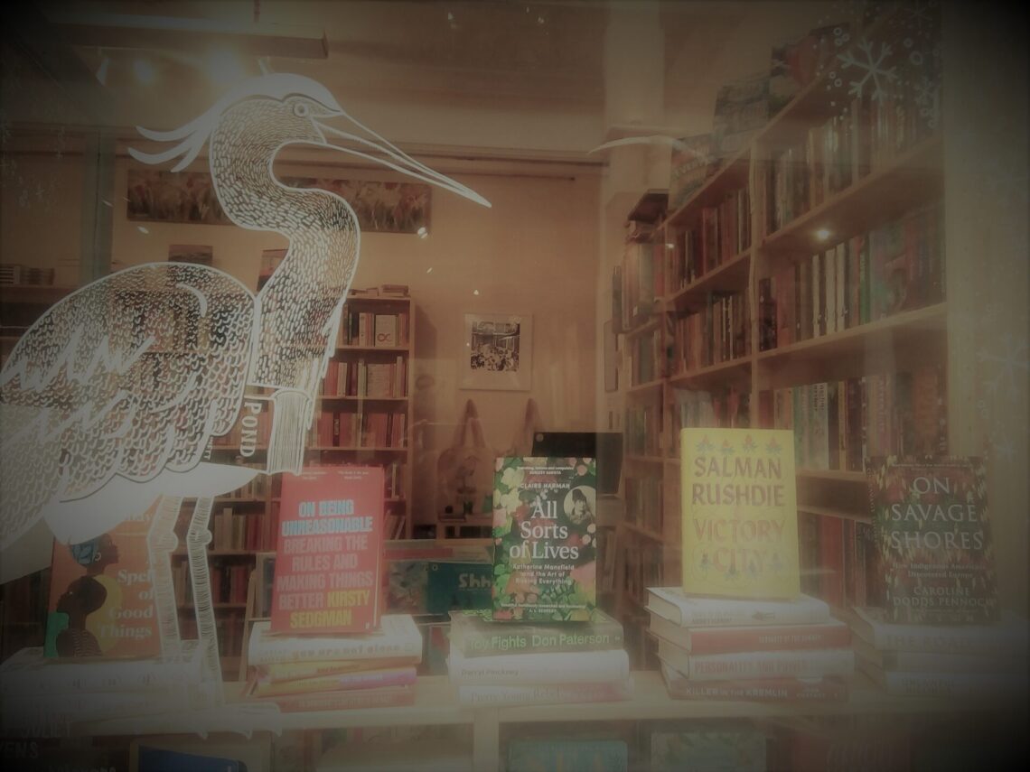 Front window of Heron Books with featured books on display.